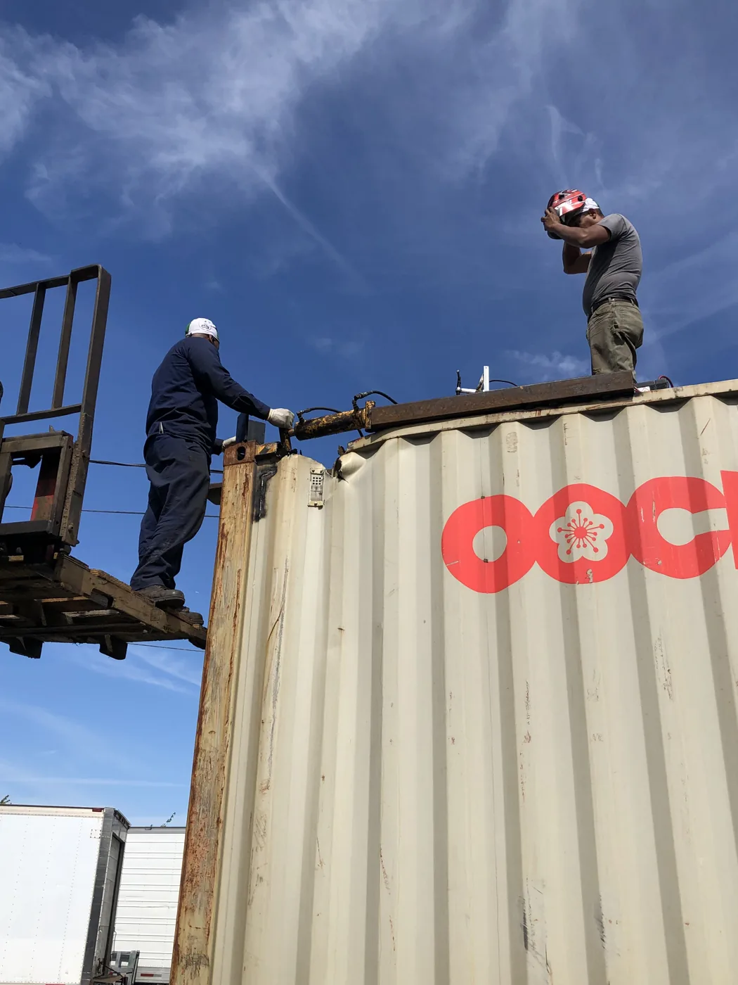 Technicians working along the top of a container